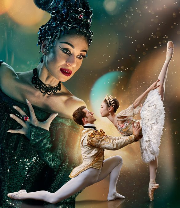 Two dancers are in the foreground looking at each other with a much larger figure in the background towering over them. The background is a blended blue and green at the top of the image. The image fades to black at the bottom. Surrounding the two dancers in the foreground is a glowing gold light with spots and streams of light surrounding the centre of the image. This gold is reflected onto the towering figure’s face. The two dancers in the foreground are towards the right of the image and are playing the characters of the Prince and Sleeping Beauty. The dancer playing the Prince has brown, short hair, is wearing white, fitted tights, white ballet flats and a cream jacket with gold detailing. He is on the left of the couple, kneeling one knee, looking up at Sleeping Beauty, with arms extended, holding her waist. The dancer playing Sleeping Beauty has dark hair in a bun, is wearing a white tutu with silver detailing, a sequinned top, sparkling tiara and is on pointe on her right leg, with her left leg extended pointing directly upwards. The figure in the background is playing Carabosse, she is positioned to the right of the foreground dancers, and is looking down at them. The dancer playing Carabosse has black hair with a silver headpiece, is wearing a gothic black dress with sequinned detailing and has black eye-makeup and red lipstick. Carabosse has her left arm clutching at her chest, a ring with large, red gemstone is on her middle finger, her right arm is extended towards the upper left and a dramatic black sleeve drapes towards the floor.