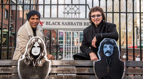 Carlos Acosta and Tony Iommi leaning on the bench on Black Sabbath Bridge in Birmingham
